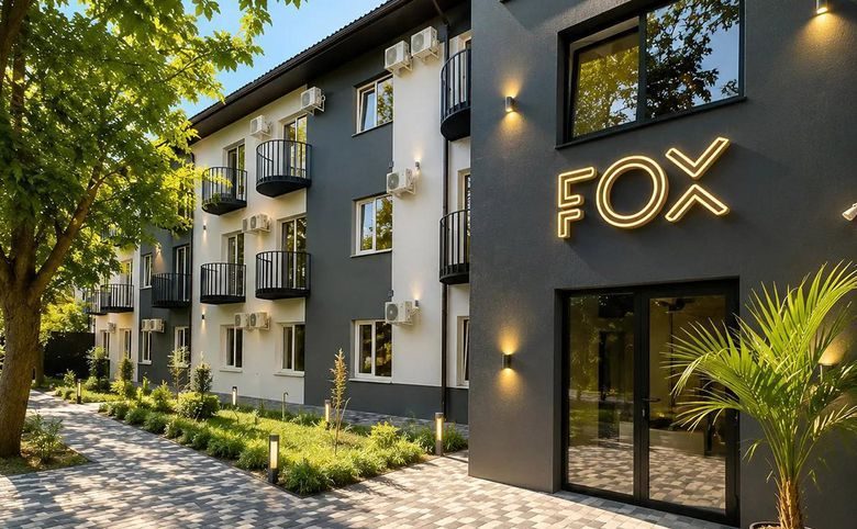 Апарт-отель Fox — Входная группа с подсветкой вывеской Fox и пальмой у двери —